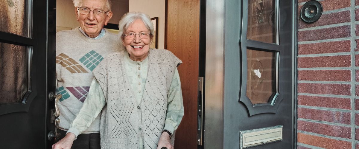 An elderly couple answering their door to a meal delivery from Meals on Wheels